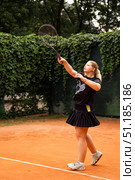 Teenage Girl Practices Her Tennis Skills on a Vibrant Outdoor Court Surrounded by Green Foliage. Стоковое фото, фотограф Aleksandr Golubev / Фотобанк Лори