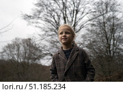 Winter clad child looking skyward through stark tree branches, soft overcast light filtering woodland scene. Стоковое фото, фотограф Данил Руденко / Фотобанк Лори
