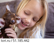 Playful Chihuahua puppy licking blonde girl's cheek, sharing tender bond of affection during heartwarming indoor cuddle moment. Стоковое фото, фотограф Данил Руденко / Фотобанк Лори