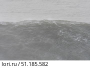 Powerful ocean wave slamming rocky coastline, churning white spray and misty atmosphere during intense storm conditions. Стоковое фото, фотограф Данил Руденко / Фотобанк Лори