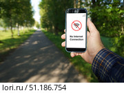 Man holding smartphone showing no internet connection in a park. Стоковое фото, фотограф Дмитрий Цветков / Фотобанк Лори