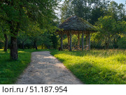 View of the ancient wooden gazebo in the apple orchard in the Mikhailovskoye Estate of the Pushkin Museum-Reserve on a sunny summer day, Pushkinskiye Gory, Pskov region, Russia. Стоковое фото, фотограф Ula Ulachka / Фотобанк Лори