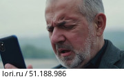 Elderly man experiences a deeply emotional response upon receiving touching news while outdoors, surrounded by serene nature. Стоковое AI-видео, аниматор Данила Большаков / Фотобанк Лори