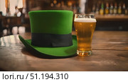 Green hat and glass of beer are placed on wooden table. Hat is neatly folded and beer looks refreshing and inviting. Setting appears casual and relaxed, perfect for laid-back gathering or social event. Стоковое AI-видео, аниматор Данила Большаков / Фотобанк Лори