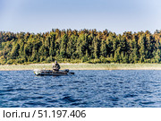 Karelia, Russia, 14 June 202, Fisherman sailing on lake in an inflatable boat (2020 год). Редакционное фото, фотограф Spirit River / Фотобанк Лори