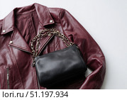 Maroon leather jacket with zippers and pockets and black leather stylish bag. Modern outerwear. Close-up. Fashion background. Autumn urban street clothes. Fashionable concept. Women's casual outfit. Стоковое AI-изображение, AI-художник Марина Демидюк / Фотобанк Лори