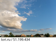 Large beautiful cumulus clouds in bright blue sky over rural area with houses, summer landscape. Стоковое фото, фотограф irisff / Фотобанк Лори