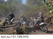 Magnitogorsk, Russian Federation - August 23, 2025: Enduro motorcycle racers navigating challenging terrain with dust clouds and obstacles, showcasing the thrill of off-road competition. Редакционное фото, фотограф Ирина Ручушкина / Фотобанк Лори