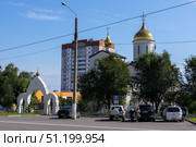 Magnitogorsk, Russian Federation - August 24, 2025: Church of the Intercession of the Most Holy Theotokos with golden domes and modern buildings in the background, showcasing urban architecture and spiritual significance. Редакционное фото, фотограф Ирина Ручушкина / Фотобанк Лори