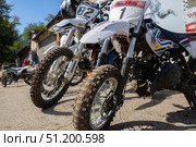 Magnitogorsk, Russian Federation - August 23, 2025: Enduro motorcycles lined up in a dirt competition area, showcasing rugged tires and vibrant designs, ready for thrilling races and adventure. Редакционное фото, фотограф Ирина Ручушкина / Фотобанк Лори
