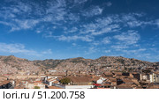 Panorama of the Cuzco city. View from the height. There are many closely built buildings with red tiled roofs. The towers of the Catholic Cathedral are visible. Mountains against a blue sky, clouds. Стоковое фото, фотограф Вера Ивановна Кубарева / Фотобанк Лори