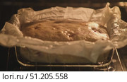 Freshly baked homemade cake rising in oven, wrapped in parchment paper inside a glass baking dish, warm golden crust forming, time lapse. Стоковое видео, видеограф Андрей Журавлев / Фотобанк Лори