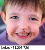 Close-up of a joyful young boy smiling with chocolate smeared around his mouth, capturing childhood fun and sweetness. A child aged four years. Стоковое фото, фотограф Андрей Журавлев / Фотобанк Лори