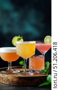 Refreshing Cocktails Served on a Wooden Tray at a Lively Bar During a Summer Evening. Стоковое AI-изображение, AI-художник Юлия Гапеенко / Фотобанк Лори