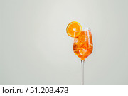 Оранжевый коктейль апероль шприц (aperol spritz) с кусочками льда и долькой апельсина в бокале на светлом фоне. Стоковое AI-изображение, AI-художник Кирилл Сиротюк / Фотобанк Лори