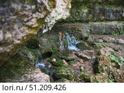Wild cave outside. The river flows out of the cave, a waterfall. Speleology and surveys. Стоковое фото, фотограф Наталия Кирсанова / Фотобанк Лори