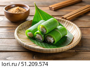 Delicious Indonesian Dadar Gulung Dessert on a Bamboo Plate. Generative AI. Стоковое AI-изображение, AI-художник Roman Zavorotny / Фотобанк Лори