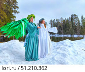 Girls in white and green dresses embodying winter and spring at a serene lakeside setting. Стоковое фото, фотограф Кривошеина Елена Леонидовна / Фотобанк Лори