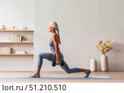 Elderly caucasian woman exercising with dumbbells in a yoga pose. Стоковое AI-изображение, AI-художник Евгения Пархоменко / Фотобанк Лори