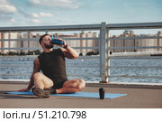 Athlete Resting and Rehydrating by the River After Outdoor Training. Стоковое фото, фотограф Aleksandr Golubev / Фотобанк Лори