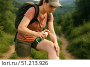 A Hiker Applying Insect Repellent During a Journey Through Lush Green Trails in Nature's Scenic Beauty. Стоковое AI-изображение, AI-художник Башкирова Анна / Фотобанк Лори