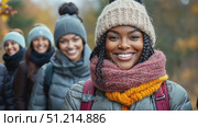 Three friends smile and pose together during their hike through a beautiful autumn forest, showcasing their warm winter attire and vibrant surroundings. Стоковое AI-видео, аниматор Данила Большаков / Фотобанк Лори