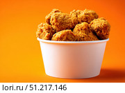 Crispy chicken on a yellow orange color background. Bucket overflowing with golden Fried Chicken Strips. Street food. Coated batter southern style chicken drumsticks and pieces. BBQ Feast. Nuggets. Стоковое AI-изображение, AI-художник Марина Демидюк / Фотобанк Лори
