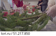 During creation of New Year's wreaths, young woman florist in gloves gives branches of Christmas tree correct shape, cutting off all excess. Стоковое видео, видеограф Strunov David / Фотобанк Лори