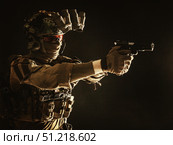 Modern soldier in combat uniform, helmet and radio headset, shooting handgun in the darkness. Oleg Zabielin / Stocktrek Images/TASS. Стоковое фото, агентство ТАСС / Фотобанк Лори
