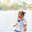 Hanoi, Vietnam - 29.04.2025: Side view portrait of cute little girl in white dress and red Non la - traditional Vietnamese straw hat standing near lake in Hanoi on sunny day. Редакционное фото, фотограф Ирина Михайличенко / Фотобанк Лори