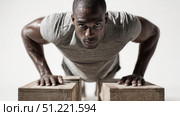 Muscular athlete performing push ups on wooden blocks, displaying powerful core strength and fitness dedication within gym environment, embodying athletic conditioning. Стоковое AI-изображение, AI-художник Юрий Поздников / Фотобанк Лори