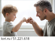 Loving father bumping fists with young son, expressing close familial connection through playful, affectionate gesture of bonding and shared joy. Стоковое AI-изображение, AI-художник Юрий Поздников / Фотобанк Лори