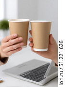 Colleagues sharing coffee break, clinking disposable cups with laptop nearby, representing workplace connection and momentary downtime during busy workday. Стоковое AI-изображение, AI-художник Юрий Поздников / Фотобанк Лори