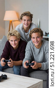 Teenage friends lounging on sofa, sharing gaming moment with controllers, immersed in multiplayer video game excitement. Стоковое AI-изображение, AI-художник Юрий Поздников / Фотобанк Лори