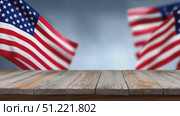 Weathered wooden table framed by vigorously waving american flags, representing national pride under bright outdoor skyline. Стоковое AI-видео, аниматор Юрий Поздников / Фотобанк Лори