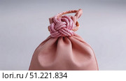 Pink decorative cord knotting delicate pouch, revealing traditional japanese wrapping technique with elegant precision against white background. Стоковое AI-видео, аниматор Юрий Поздников / Фотобанк Лори