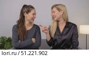 Young female professionals networking, sitting together and sharing laughs, gesturing animatedly against minimalist grey backdrop, embodying collaborative workplace energy. Стоковое AI-видео, аниматор Юрий Поздников / Фотобанк Лори