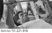 Muscular athlete bench pressing heavy weights, showcasing powerful physique and intense training commitment in monochrome gym setting. Стоковое AI-видео, аниматор Юрий Поздников / Фотобанк Лори