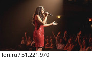 Female vocalist wearing shimmering red sequin gown, singing with intensity while connecting with energetic crowd under dramatic stage lighting. Стоковое AI-видео, аниматор Юрий Поздников / Фотобанк Лори