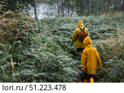 Tourism. Hiking. Ladoga skerries. Father and son tourists in yellow raincoats on stone islands in the forest. Republic of Karelia, Russia. Стоковое фото, фотограф Photojuli / Фотобанк Лори