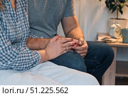 Couple holding hands at home. Happy Man and Woman. Two Loving Hands Together on the Couch Sharing Deep Affection and Love in Details. Intimate connection. Close-up of Intertwined female and male hands. Стоковое фото, фотограф Марина Демидюк / Фотобанк Лори