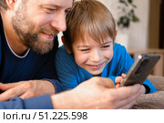 Father and son little boy laughing and using phone. They watching funny videos together, playing games on smartphone. Concept technology, smart phone addicted. Fun weekend activity. Modern fatherhood. Стоковое фото, фотограф Марина Демидюк / Фотобанк Лори