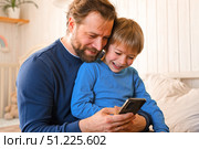 Father and son little boy laughing and using phone. They watching funny videos together, playing games on smartphone. Concept technology, smart phone addicted. Fun weekend activity. Modern fatherhood. Стоковое фото, фотограф Марина Демидюк / Фотобанк Лори