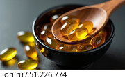 Bowl and spoon with golden omega capsules on gray background. Concept: the role of fatty acids in maintaining health. AI generative. Стоковое AI-изображение, AI-художник Роман Дзюбало / Фотобанк Лори