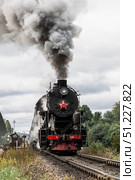 An old Soviet steam locomotive of the L series. The Ruskeala Express retro train is on its way to the mountain park. Thick smoke is coming from the chimney. Russia, Republic of Karelia, Sortavala, August 11, 2025. Редакционное фото, фотограф Photojuli / Фотобанк Лори