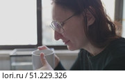 Woman enjoying hot beverage by window. Стоковое видео, видеограф Константин Шишкин / Фотобанк Лори