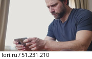Man using his cellphone. Handsome guy use mobile phone at home. Male browses social networks, gaming, does shopping online, chats with friends, writes or reads messages. Close up. 4k video footage. Стоковое видео, видеограф Марина Демидюк / Фотобанк Лори
