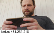 Man using his cellphone. Handsome guy use mobile phone at home. Male browses social networks, gaming, does shopping online, chats with friends, writes or reads messages. Close up. 4k video footage. Стоковое видео, видеограф Марина Демидюк / Фотобанк Лори