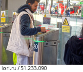 St.Petersburg, Russia-August 17,2025:Young man scanning QR code on train ticket on turnstile scanner to board train at train station. Редакционное фото, фотограф Андрей Митин / Фотобанк Лори