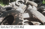 A large stack of old, dirty tires fills an empty lot under bright sunlight. The sight reveals a pressing environmental challenge regarding waste disposal and management in urban areas. Стоковое видео, видеограф Громов Александр / Фотобанк Лори